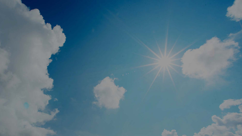 Image of the blue sky with a bright sun and white fluffy clouds