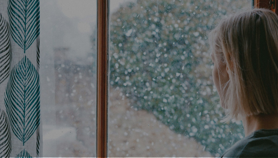 Sad woman looking outside a window in the winter